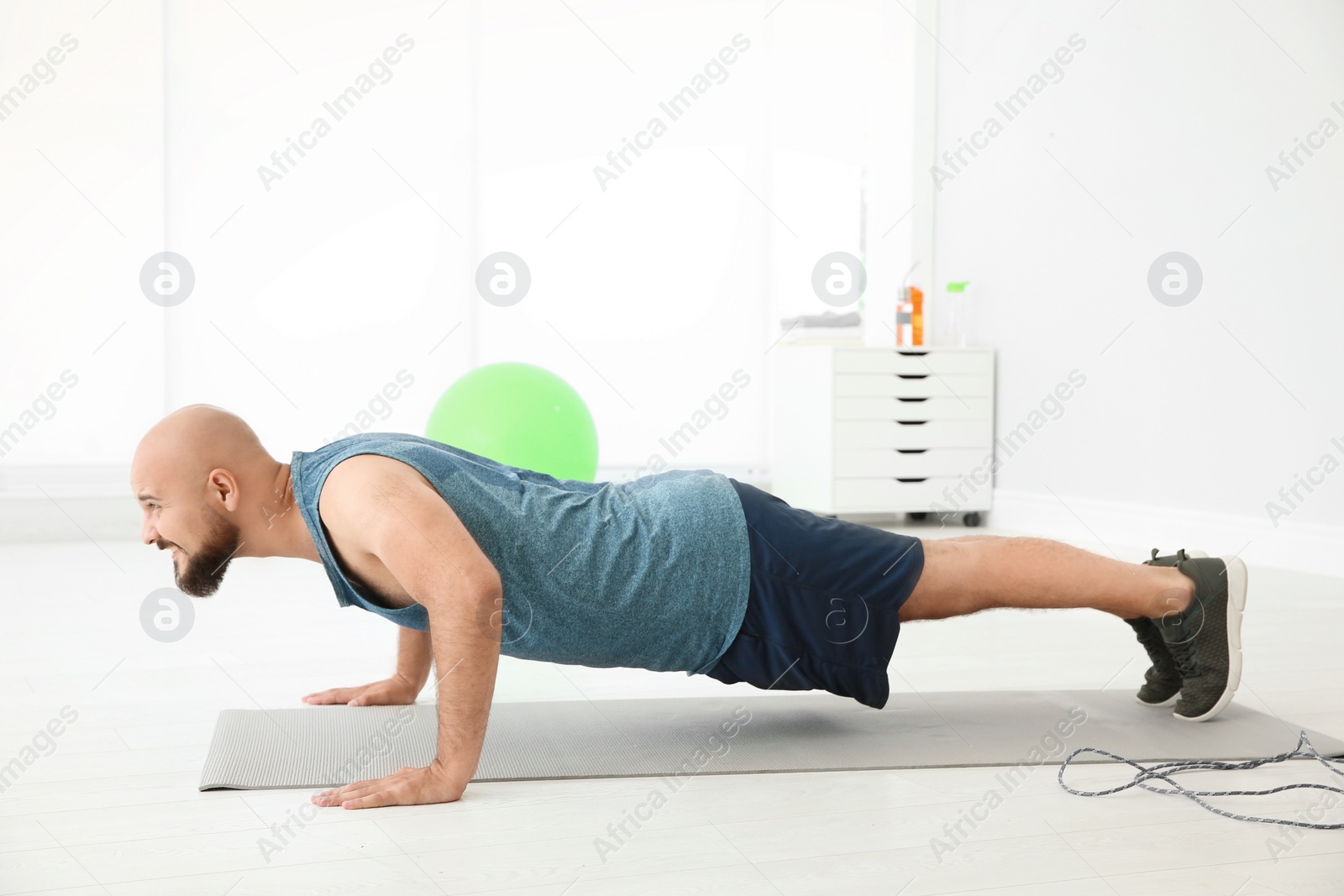 Photo of Overweight man doing exercise on floor in gym