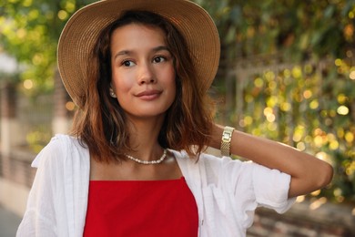 Photo of Portrait of beautiful stylish young woman in straw hat on city street