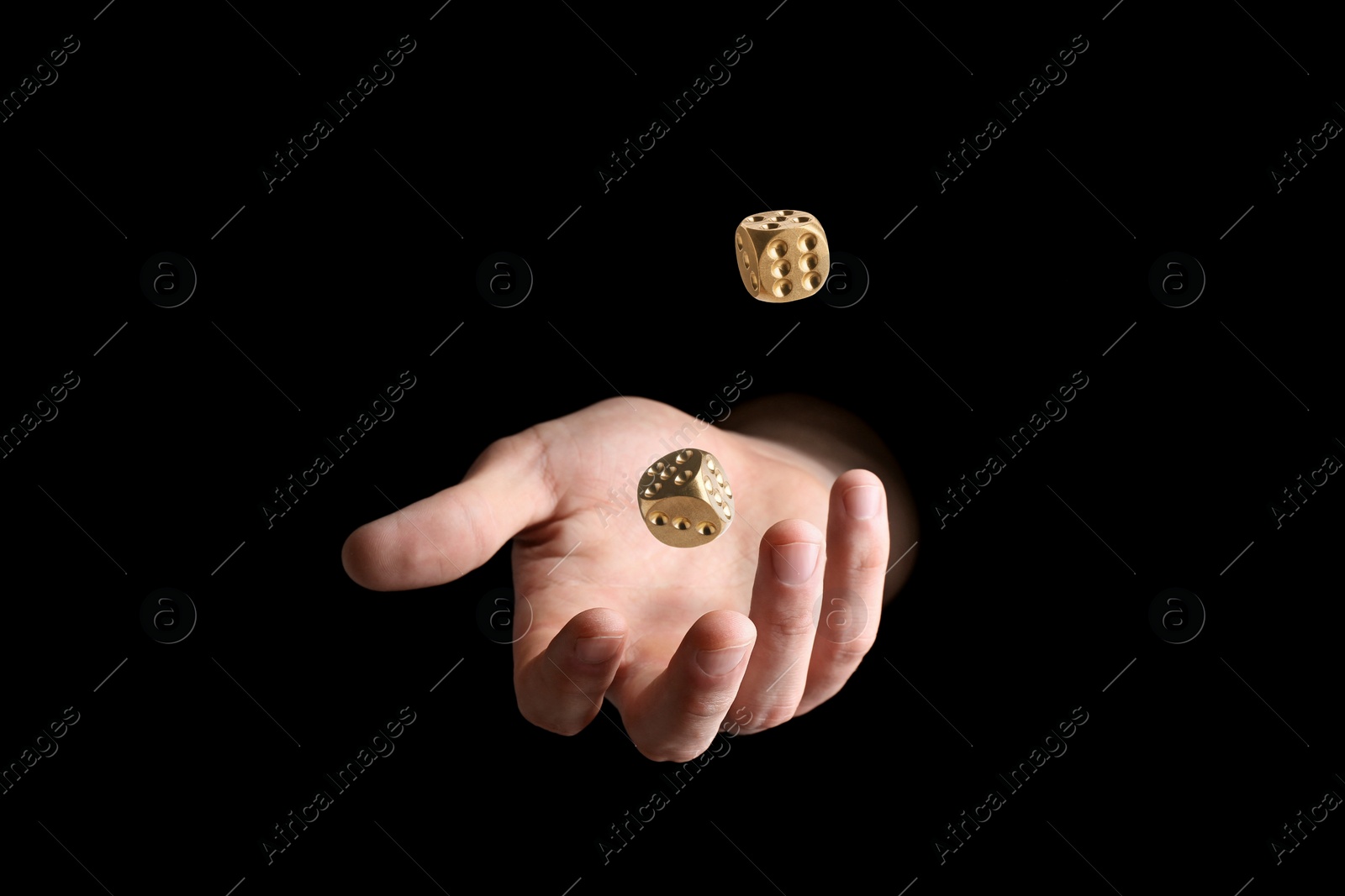 Image of Man throwing golden dice on black background, closeup