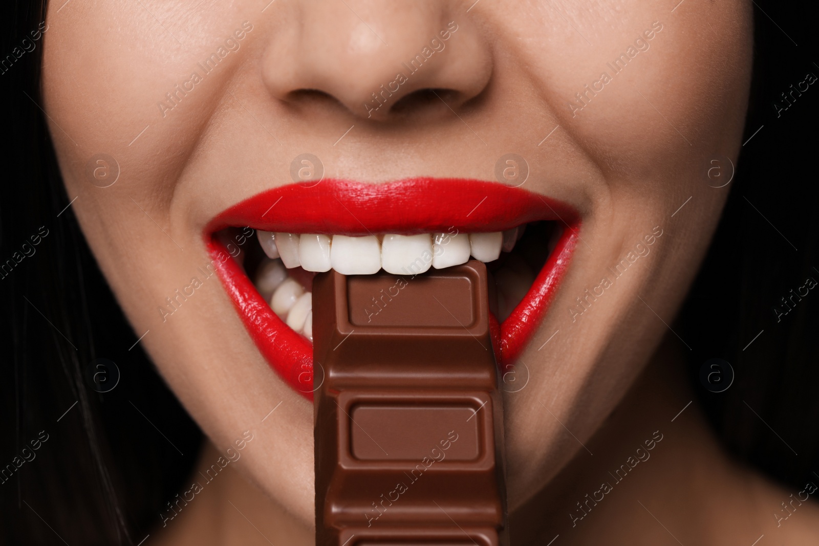 Photo of Young woman with red lips eating chocolate, closeup