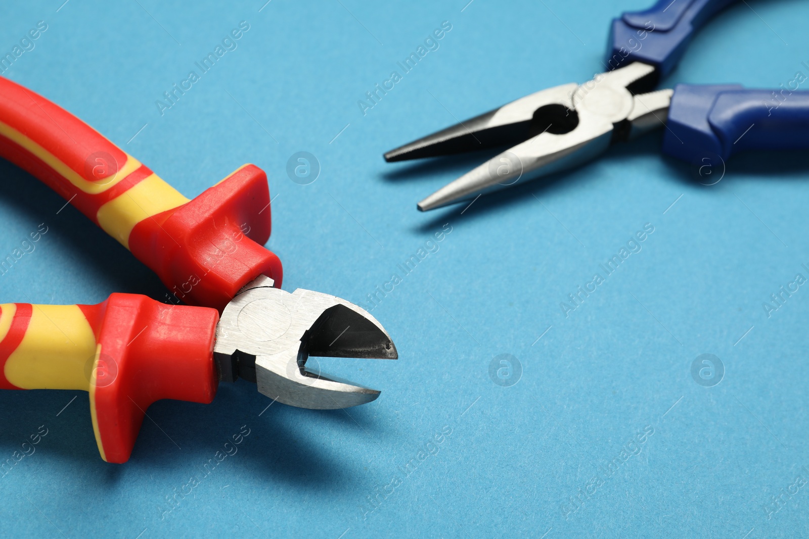 Photo of Pliers on light blue background, closeup view