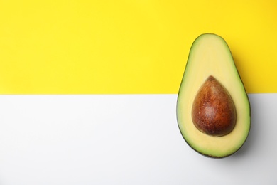 Photo of Cut fresh ripe avocado on color background, top view with space for text