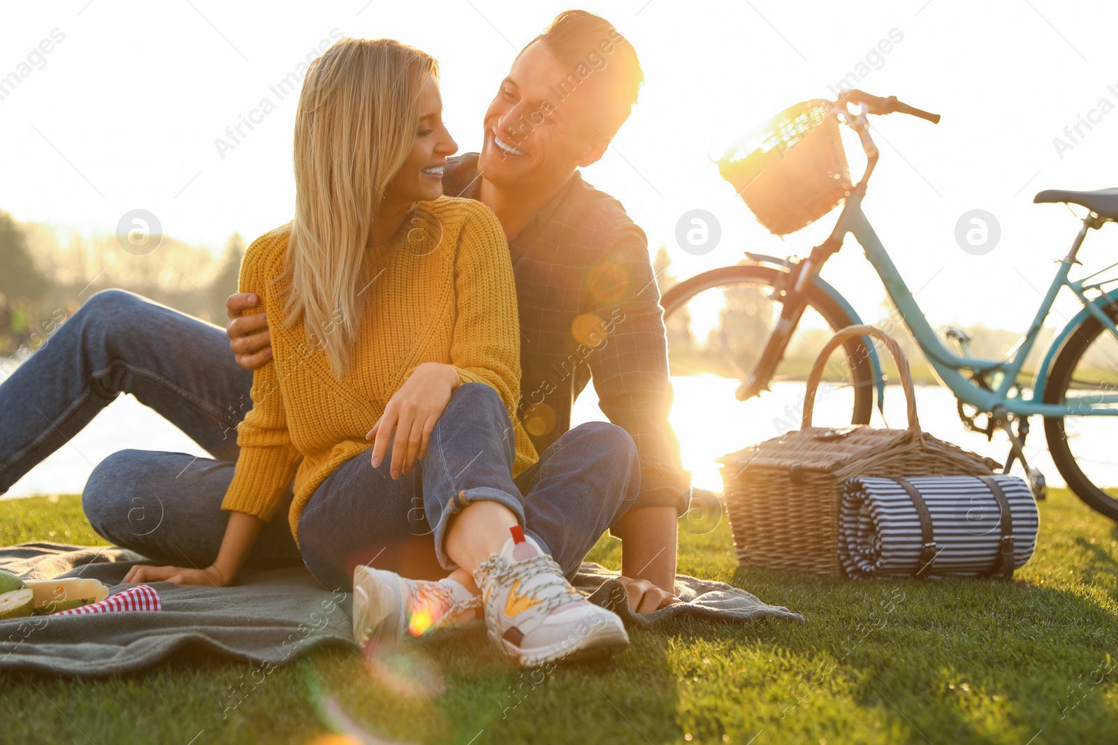 Photo of Happy young couple having picnic near lake on sunny day