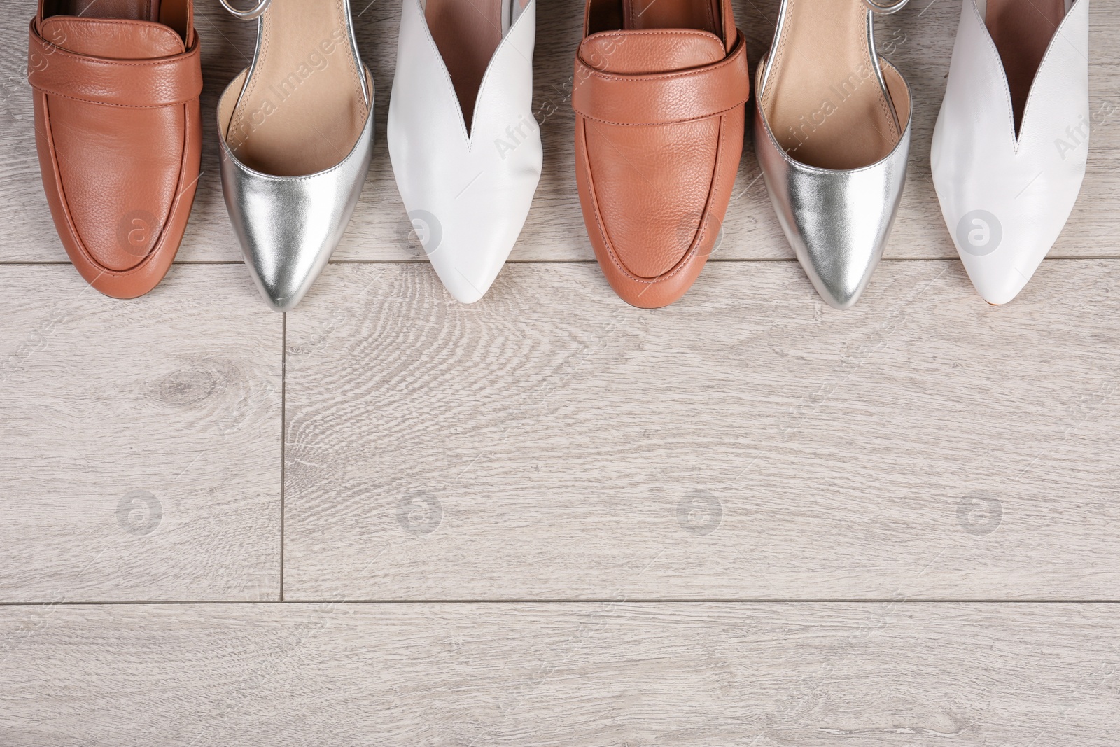 Photo of Different female shoes on wooden background, top view