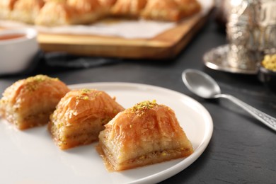 Photo of Delicious sweet baklava with pistachios on black table, closeup