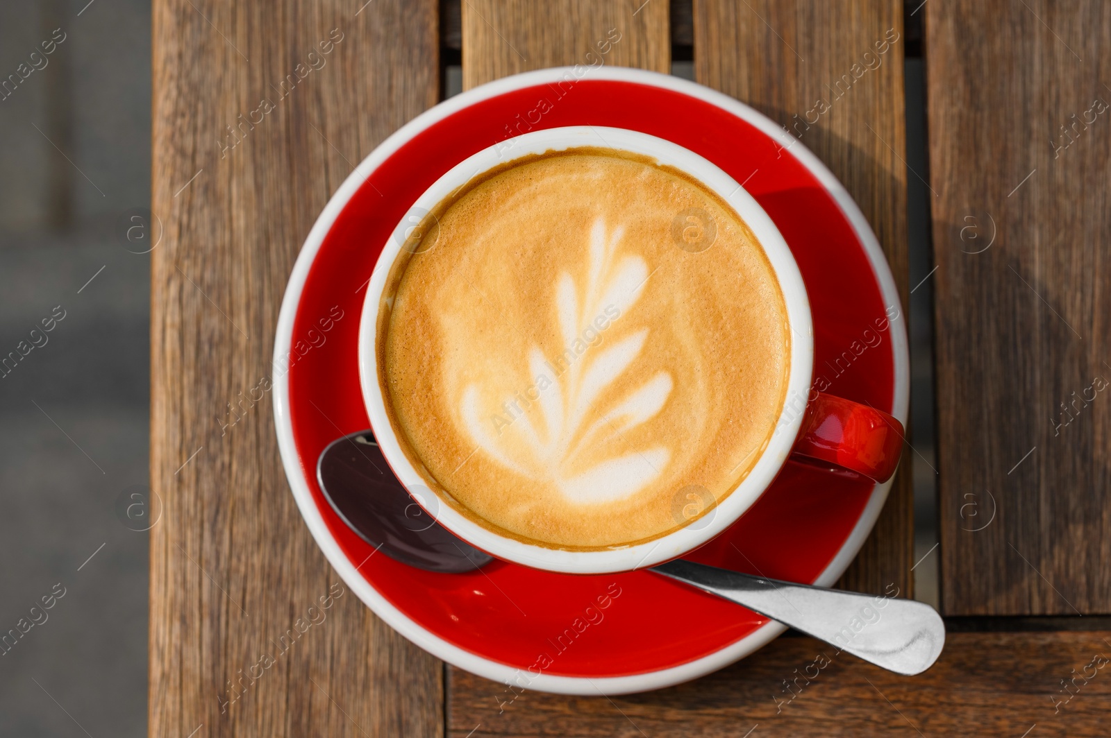 Photo of Cup of aromatic coffee on wooden table, top view