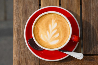 Photo of Cup of aromatic coffee on wooden table, top view