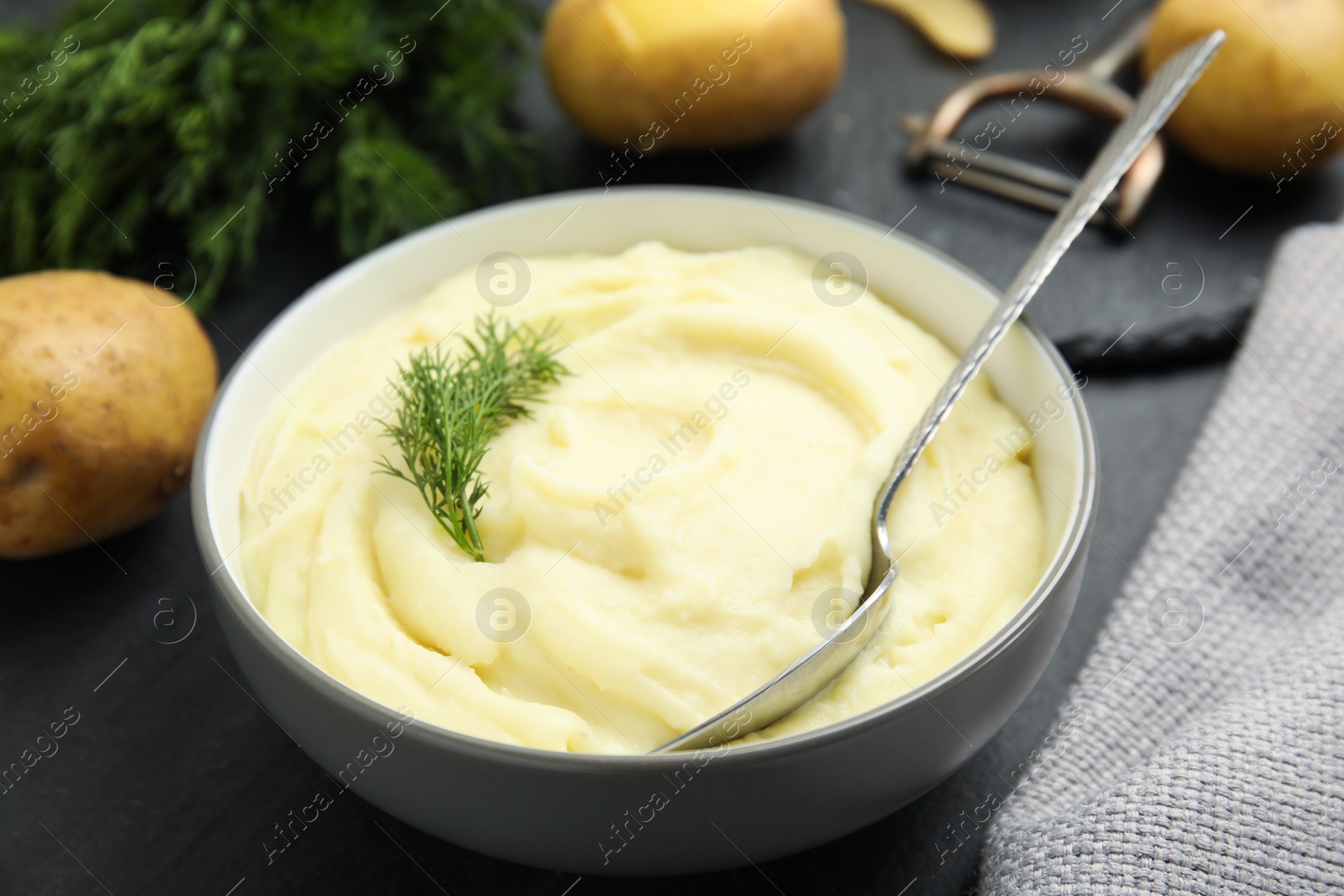 Photo of Freshly cooked homemade mashed potatoes on dark grey table, closeup
