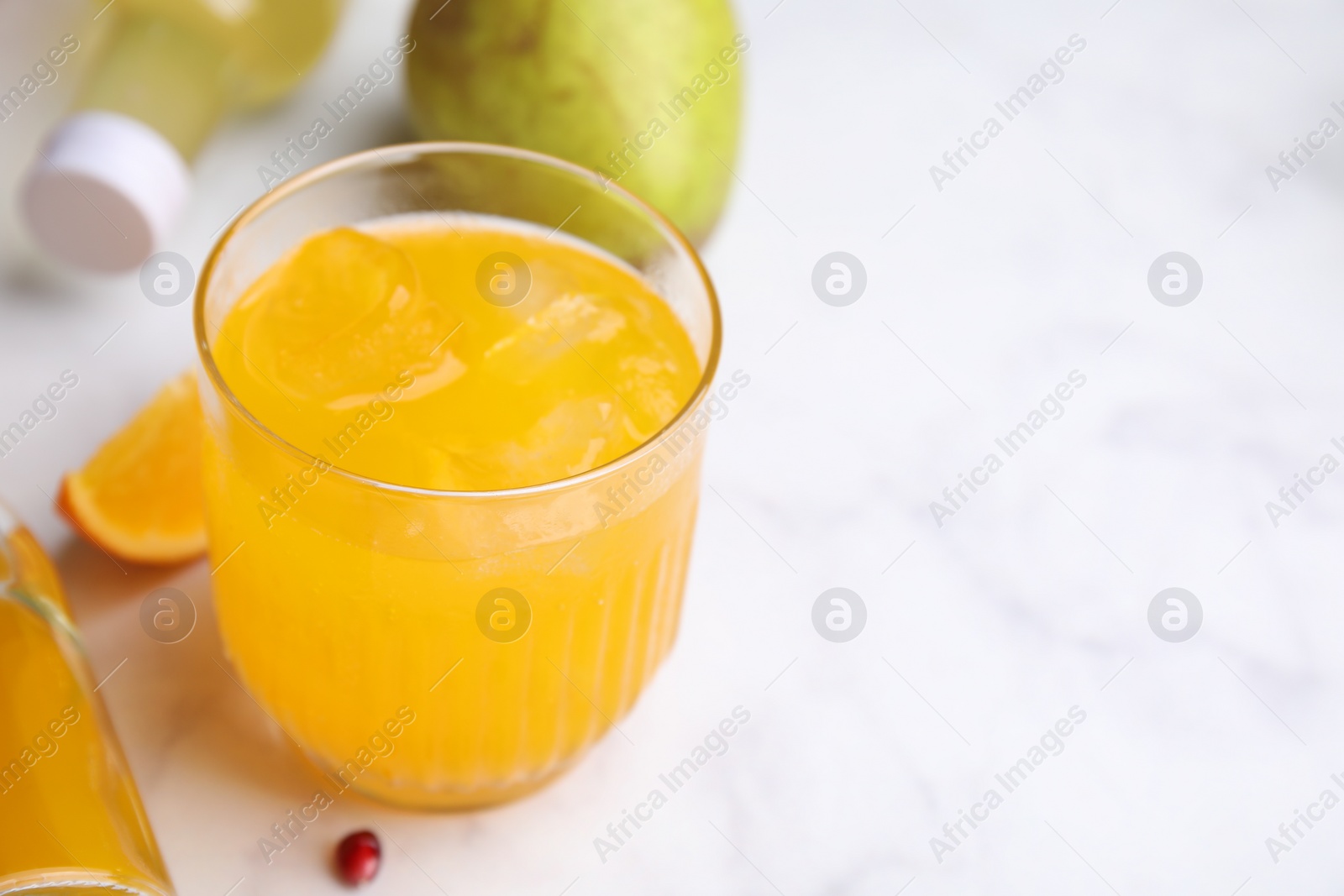 Photo of Tasty kombucha in glass with ice on white table, closeup. Space for text