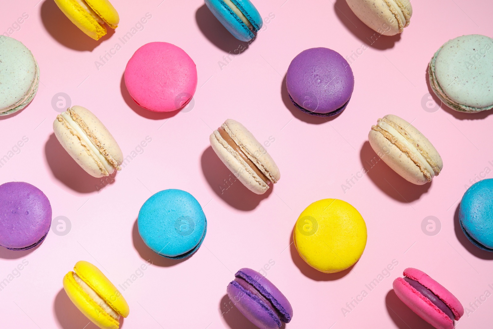 Photo of Delicious colorful macarons on pink background, flat lay