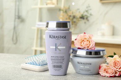 Photo of MYKOLAIV, UKRAINE - SEPTEMBER 07, 2021: Kerastase hair care cosmetic products and brush on light table in bathroom