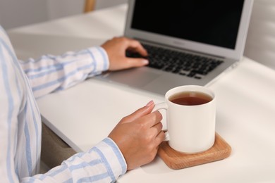 Photo of Woman with white ceramic mug at workplace, closeup