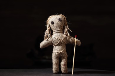 Photo of Voodoo doll with match on black table. Curse ceremony