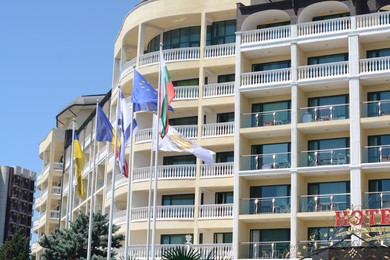 Photo of Many different flags near modern hotel on sunny day