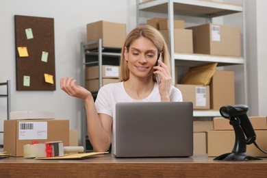 Photo of Seller talking on phone while working in office. Online store