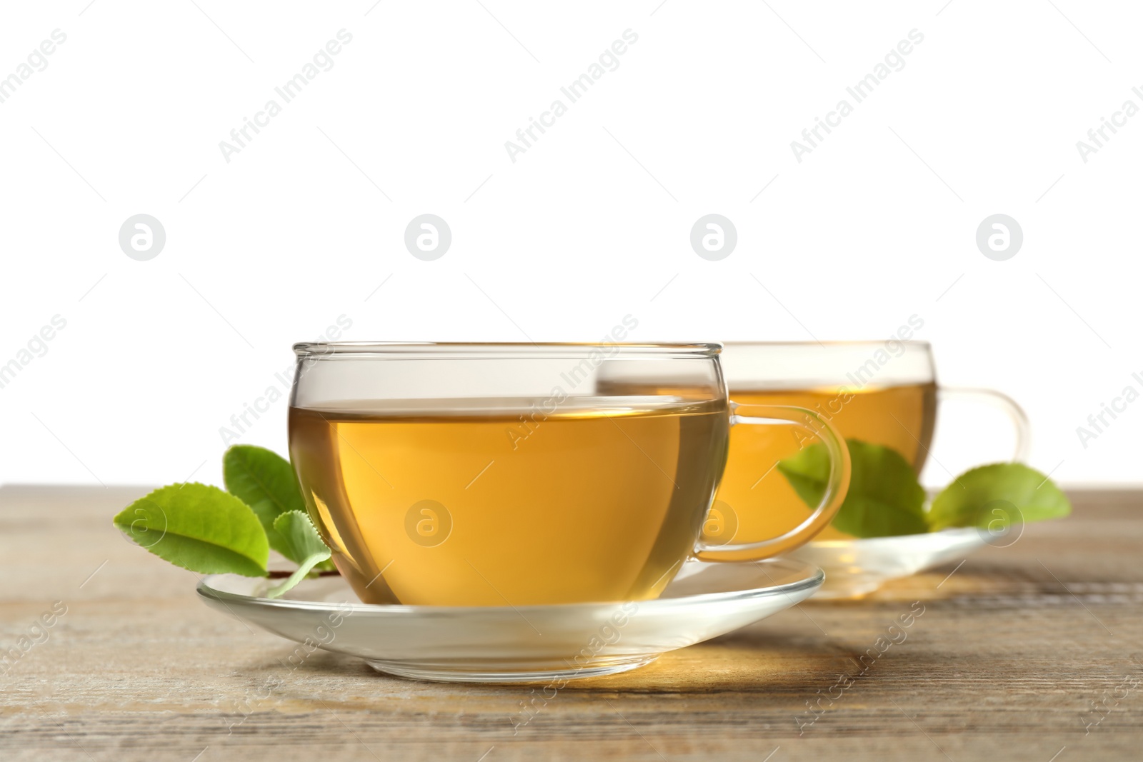 Photo of Cups of green tea and leaves on wooden table