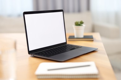 Photo of Laptop with blank screen on wooden table in room