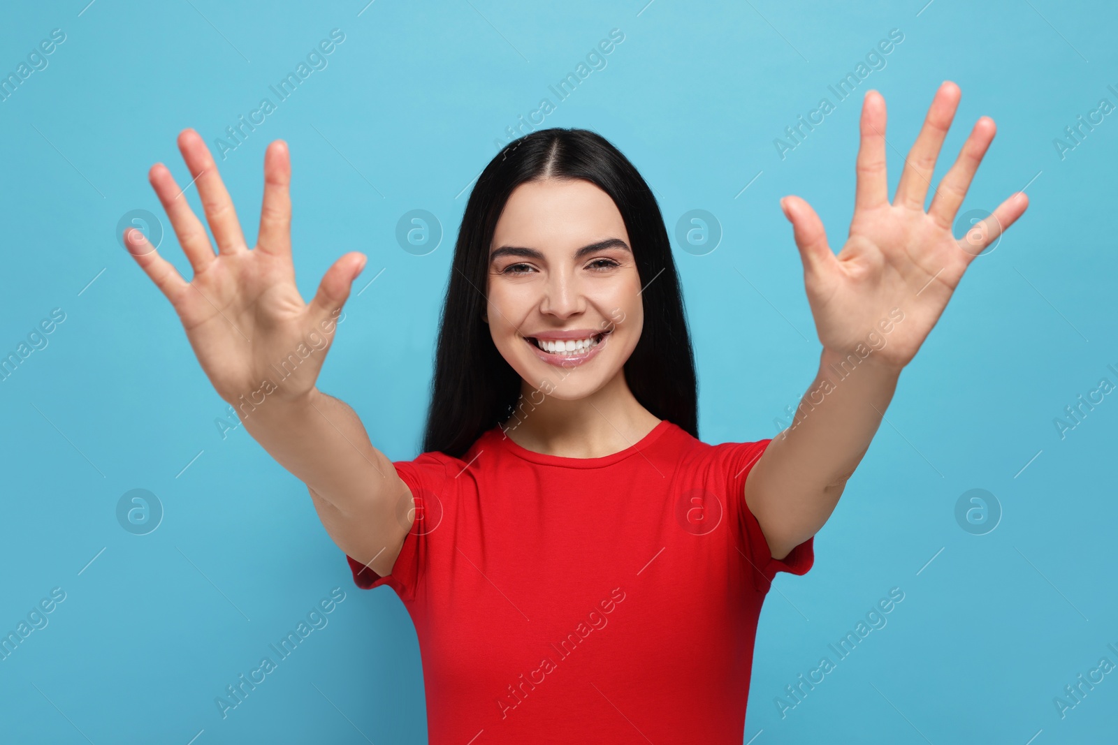 Photo of Happy woman giving high five with both hands on light blue background