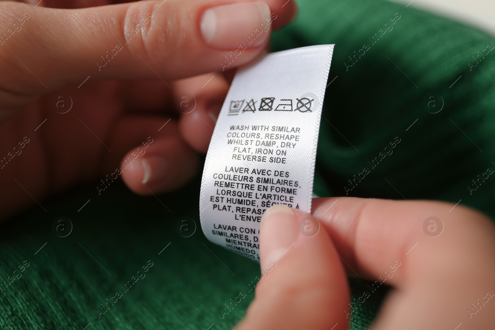 Photo of Woman reading clothing label with care symbols on green shirt, closeup