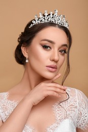 Photo of Beautiful young woman wearing luxurious tiara on beige background