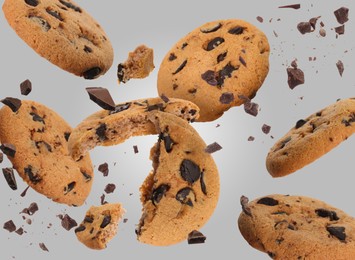 Image of Tasty chocolate chip cookies falling on light grey background