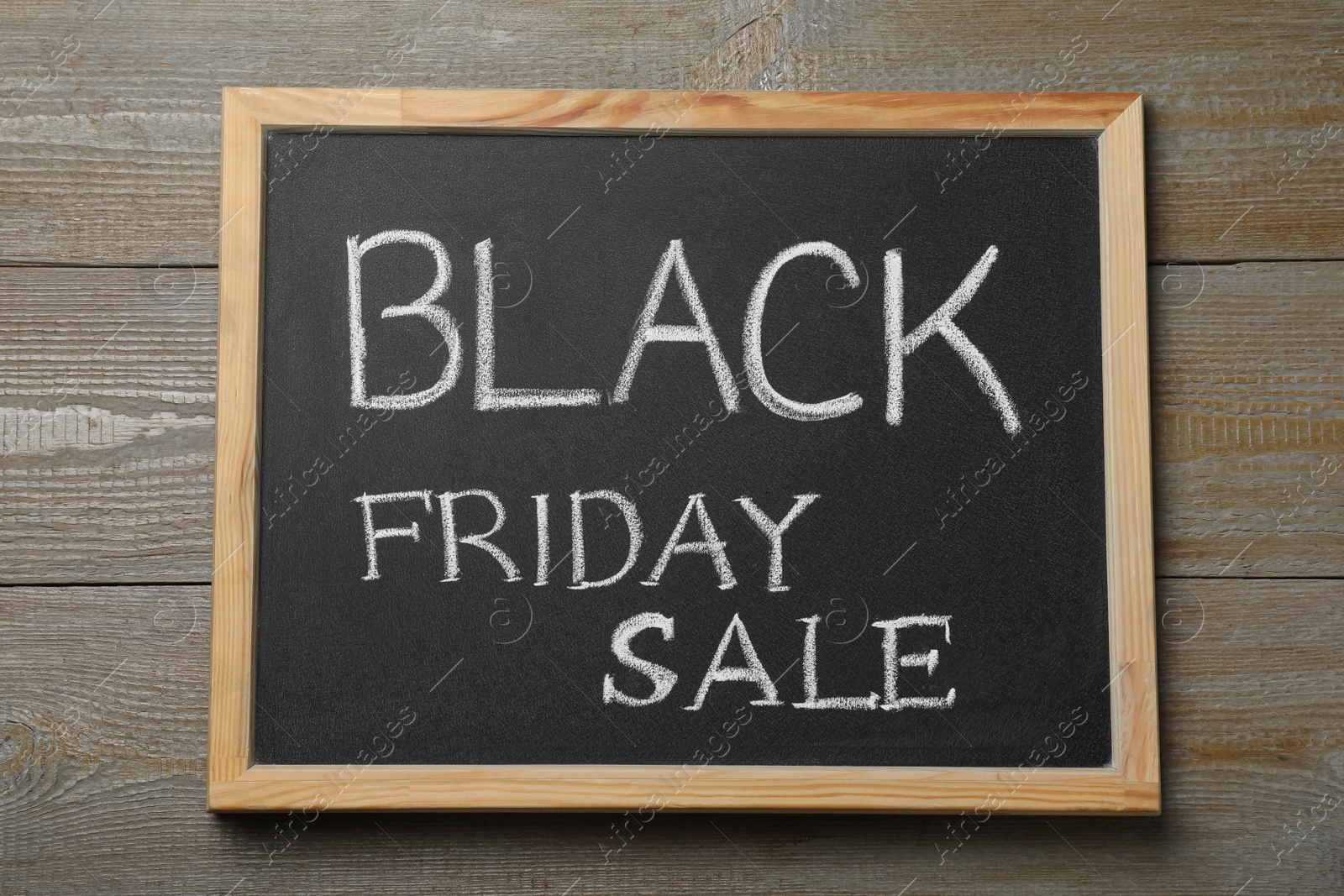Photo of Chalkboard with words Black Friday Sale on wooden table, top view