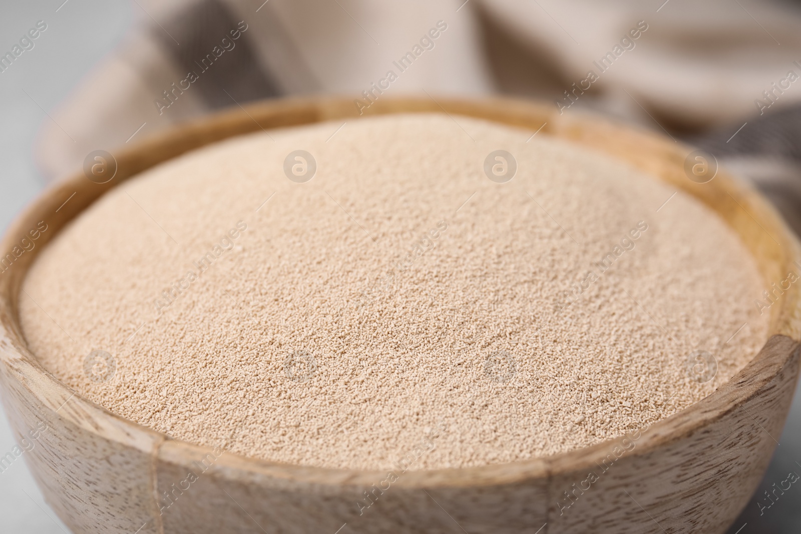 Photo of Granulated yeast in wooden bowl, closeup view