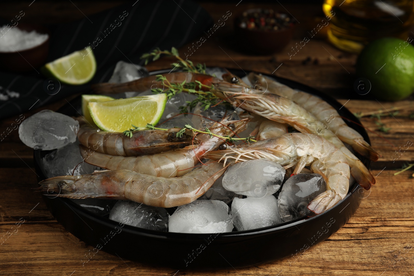 Photo of Fresh raw shrimps with ice on wooden table