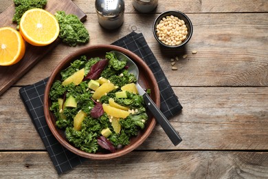 Photo of Tasty fresh kale salad on wooden table, flat lay