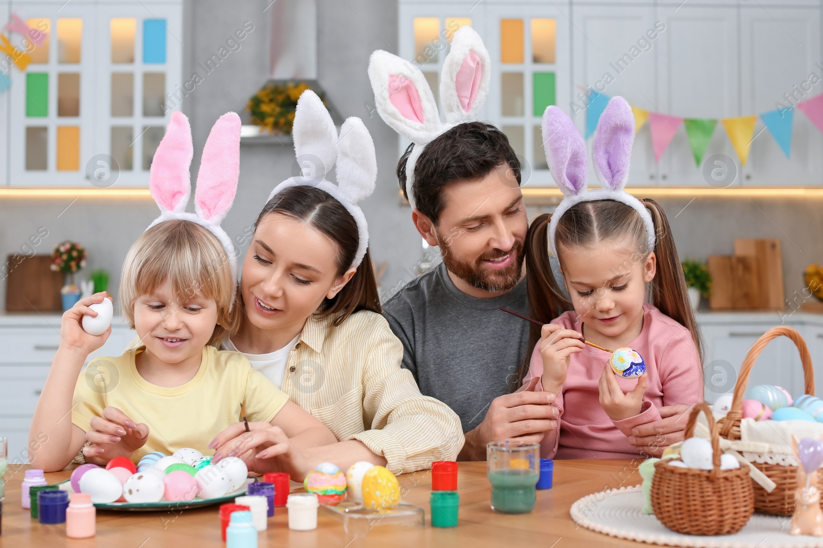 Photo of Happy family painting Easter eggs at table in kitchen