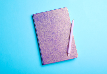 Photo of Stylish glitter notebook and pen on light blue background, top view