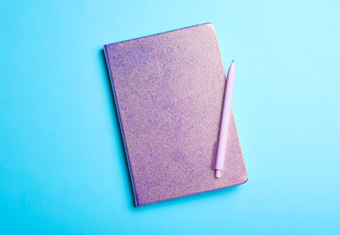 Stylish glitter notebook and pen on light blue background, top view