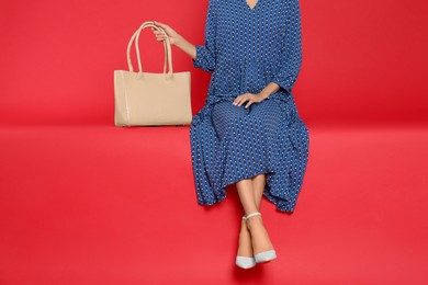 Woman with stylish bag on red background, closeup