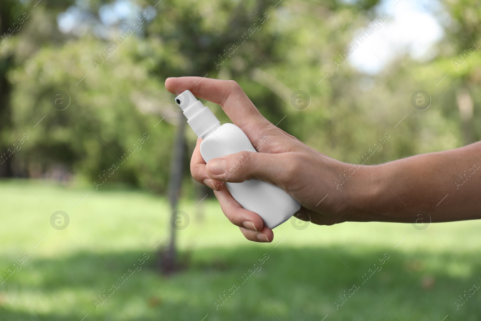 Photo of Woman with bottle of insect repellent spray outdoors, closeup