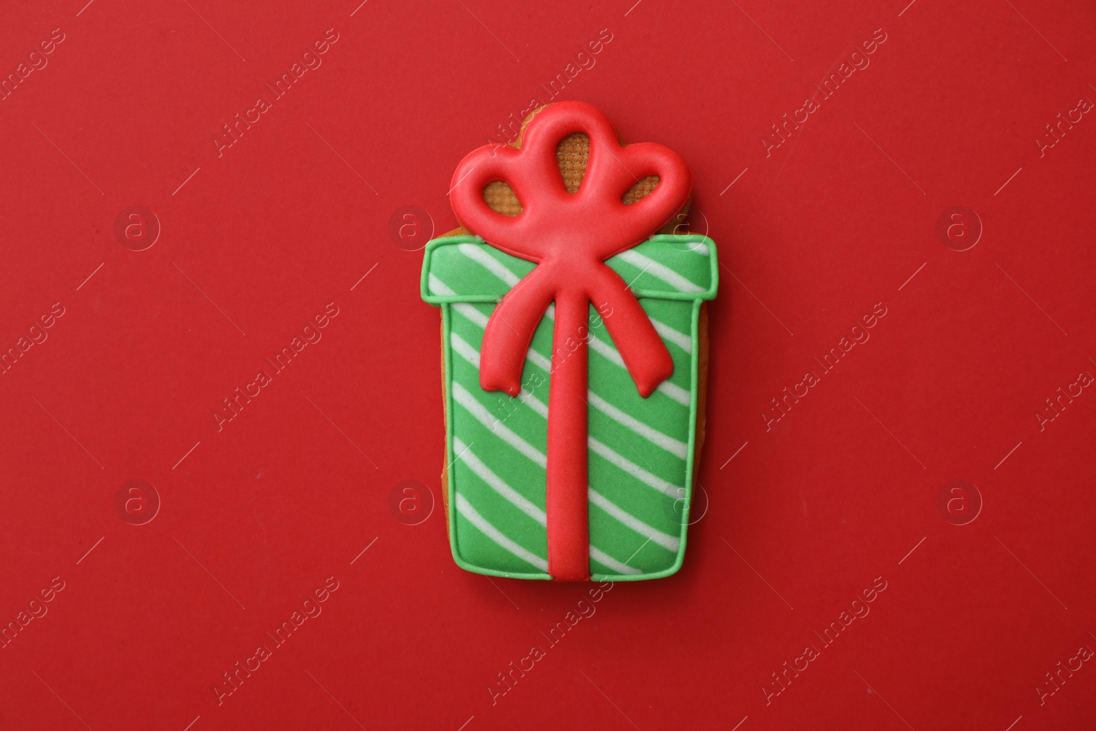 Photo of Christmas gift shaped gingerbread cookie on red background, top view