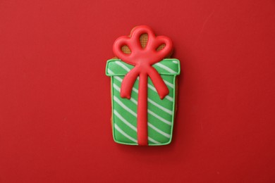 Christmas gift shaped gingerbread cookie on red background, top view
