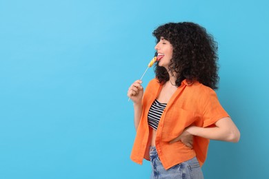 Beautiful woman with lollipop on light blue background, space for text