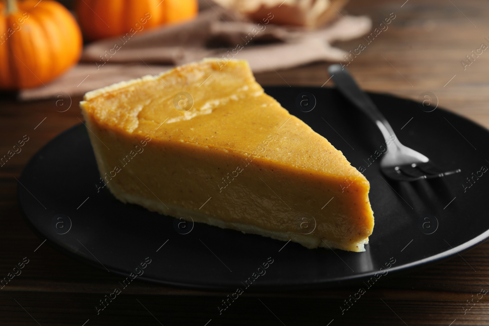 Photo of Piece of delicious pumpkin pie and fork on table, closeup