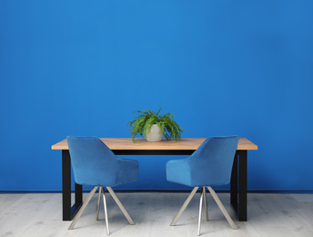 Photo of Modern table with potted fern near blue wall