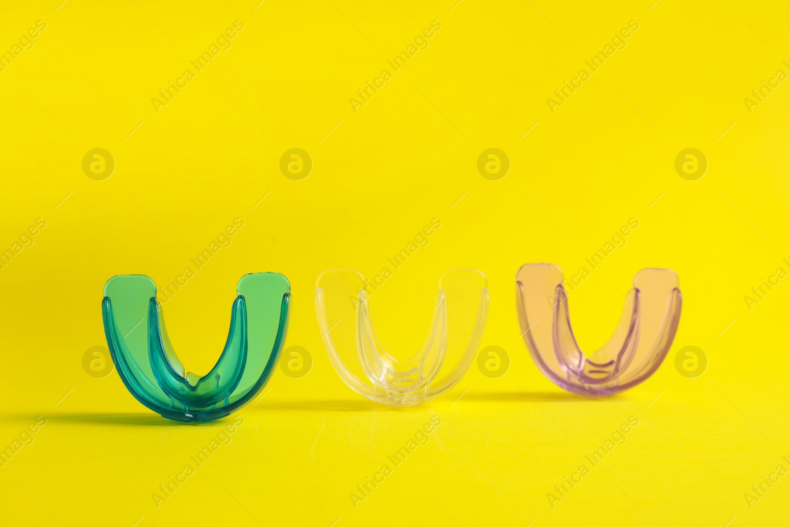 Photo of Transparent dental mouth guards on yellow background. Bite correction