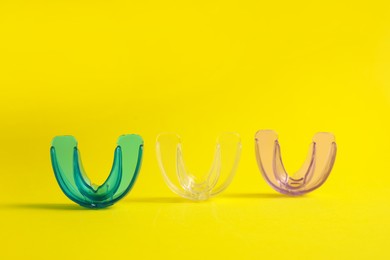 Transparent dental mouth guards on yellow background. Bite correction