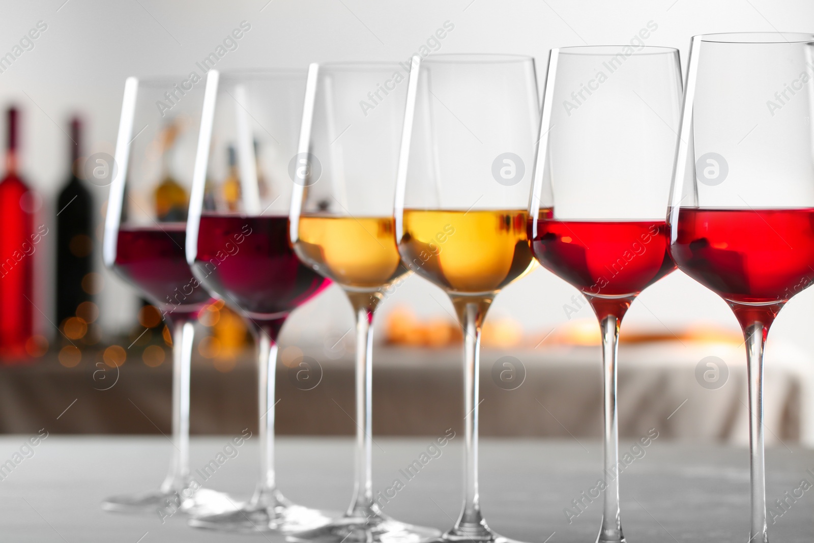 Photo of Row of glasses with different wines on table against blurred background