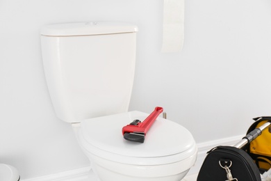 Plumber wrench on toilet bowl lid in bathroom