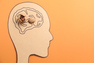 Photo of Amnesia problem. Paper cutout of human head, brain drawing and broken walnut on orange background, top view. Space for text