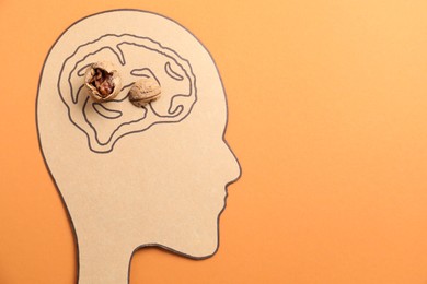 Amnesia problem. Paper cutout of human head, brain drawing and broken walnut on orange background, top view. Space for text