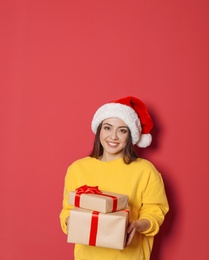 Young woman with Christmas gifts on color background