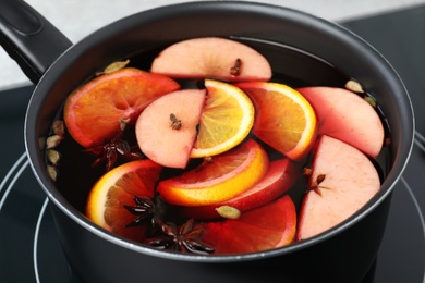 Photo of Delicious hot mulled wine on stove, closeup