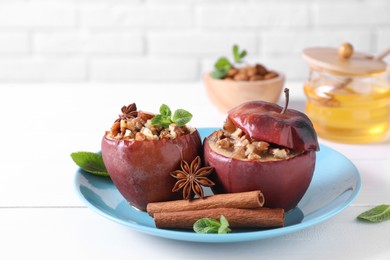 Tasty baked apples with nuts, honey, spices and mint on white wooden table