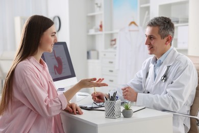 Photo of Gastroenterologist consulting patient at table in clinic