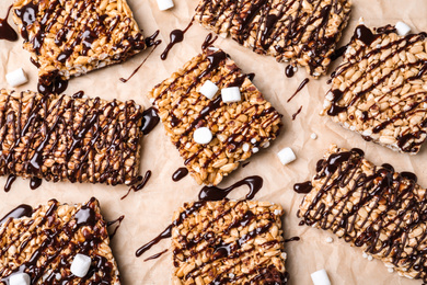 Photo of Delicious rice crispy treats on parchment paper, flat lay